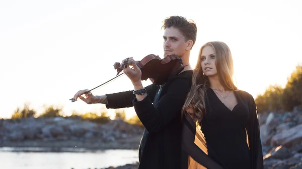 Violinist and girl,  young man plays on the background of  sea — Stock Photo, Image