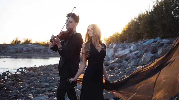 Violinist and girl,  young man plays on the background of  sea — Stock Photo, Image