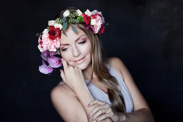 Jovem bela mulher na grinalda de flores de mãos dadas face a face, fundo preto — Fotografia de Stock