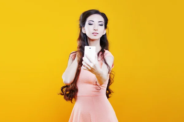 Fashion asian young  girl   taking picture of herself, selfie. Portrait on yellow background — Stock Photo, Image