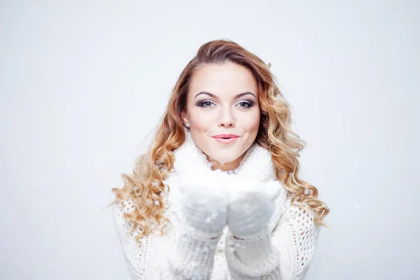 Mujer que sopla nieve, chica en bufanda de punto cálido y guantes, retrato sobre fondo blanco, lugar para su texto —  Fotos de Stock