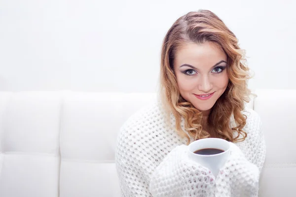 Jeune femme à la maison boire du café chaud, enveloppé dans un foulard, fond blanc, endroit pour votre texte — Photo