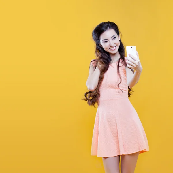 时尚亚洲年轻女孩拍照的自己，自拍照。在黄色背景上的肖像 — 图库照片
