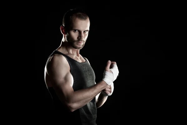 Homem muscular, amarrando uma bandagem elástica em sua mão, fundo preto — Fotografia de Stock