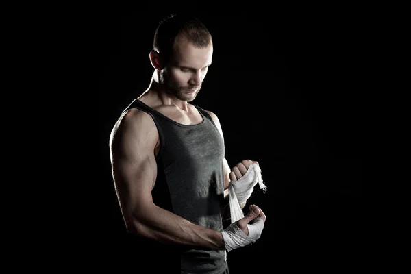 Muskularny mężczyzna, wiązanie bandaż elastyczny na ręku, czarne tło — Zdjęcie stockowe