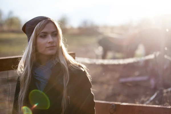 Young beautiful girl in a stable, outdoors,  photo with warm toning, rays of sun — Φωτογραφία Αρχείου