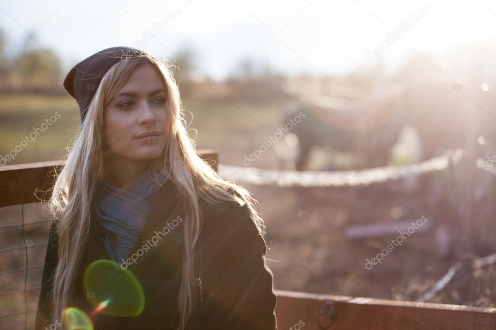 young beautiful girl in a stable, outdoors,  photo with warm toning, rays of sun