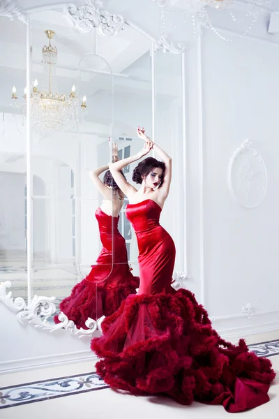 Belleza Morena modelo mujer en vestido rojo noche. Maquillaje y peinado de lujo de moda hermosa, longitud completa con espejos — Foto de Stock