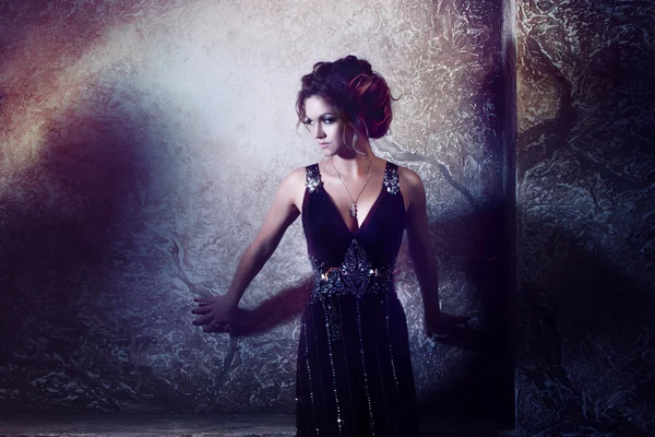 Jeune belle femme en robe longue contre le mur, style sombre, atmosphère mystérieuse — Photo