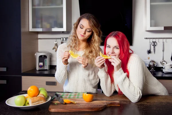 Duas meninas na cozinha conversando e comendo frutas, estilo de vida saudável — Fotografia de Stock