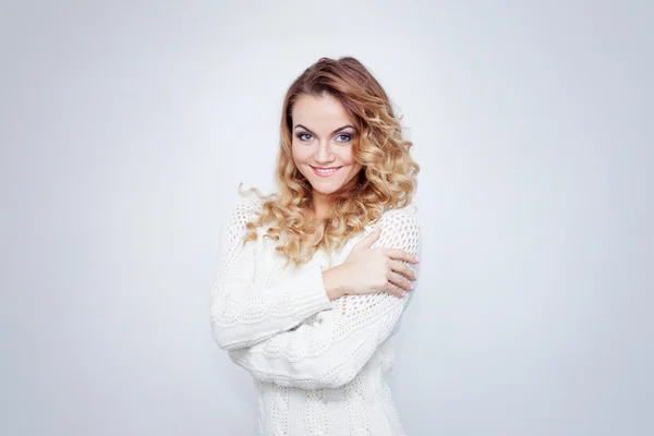 Ritratto di giovane donna felice isolata su sfondo bianco, ragazza in un maglione caldo sorridente e guardando la macchina fotografica — Foto Stock