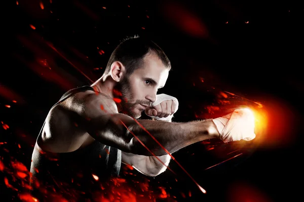 Muscular man, tying an elastic bandage on his hand, black background — Stock Photo, Image