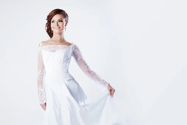 Bela noiva em vestido de noiva, segura bainha de vestido e sorrindo, espaço para texto à direita — Fotografia de Stock