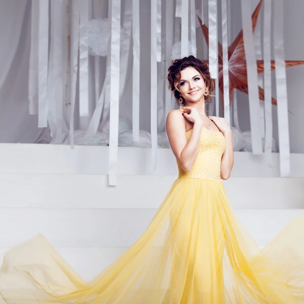 Smiling woman in yellow evening dress and with beautiful hairstyle, party — Stock Photo, Image