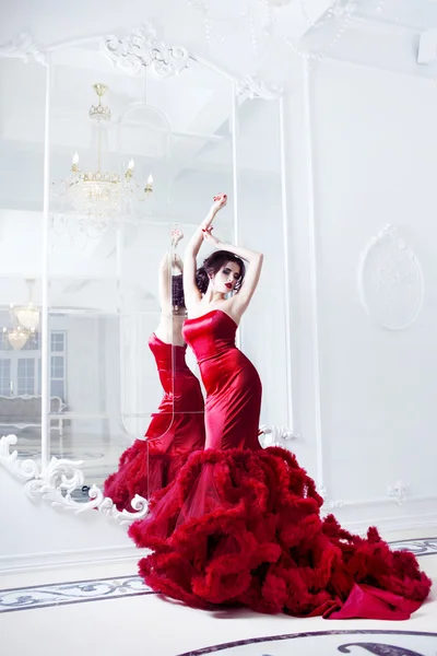 Belleza Morena modelo mujer en vestido rojo noche. Maquillaje y peinado de lujo de moda hermosa, longitud completa con espejos —  Fotos de Stock