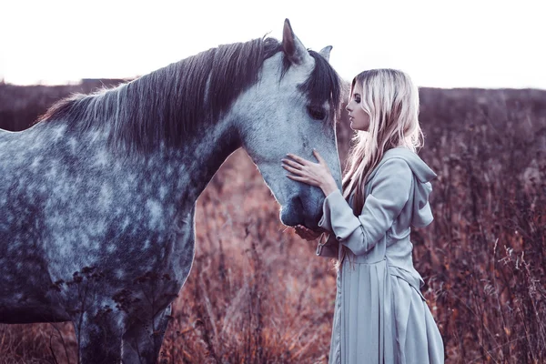 Loirinha de beleza com cavalo no campo, efeito de tonificação — Fotografia de Stock