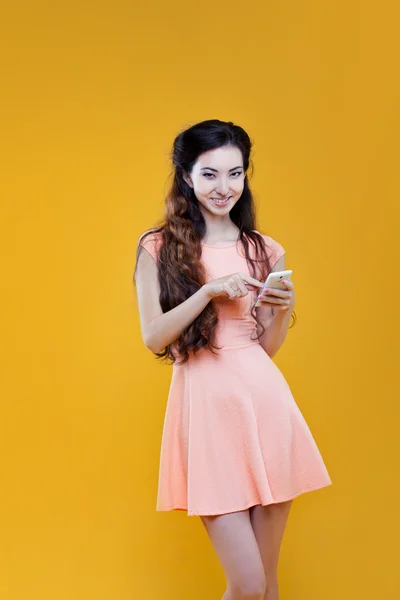 亚洲年轻女孩时尚与移动电话。在黄色背景上的肖像 — 图库照片