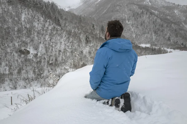 Člověk se modlí, aby seděl ve sněhu v horách. — Stock fotografie