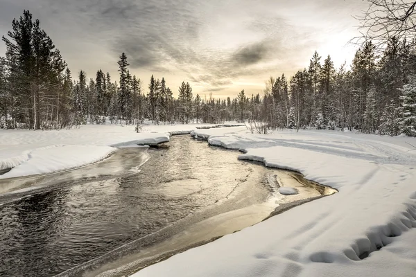 Sneeuw bedekte riverbank onder het avondrood. Noord-Karelia. Rusland. — Stockfoto