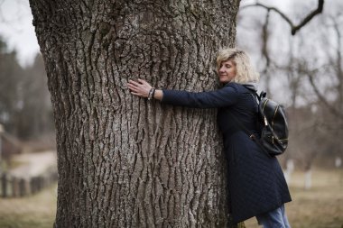 Güzel sarışın kız ağaç gövdesi sarılma