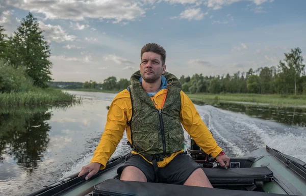 Brave handsome man is operating of boat on the river — Stock Photo, Image