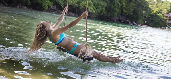 Mulher de biquíni azul em baloiços de corda — Fotografia de Stock