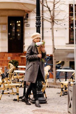 Bere takmış bir kadın ve bir buket çiçeğin tadını çıkarıyor.