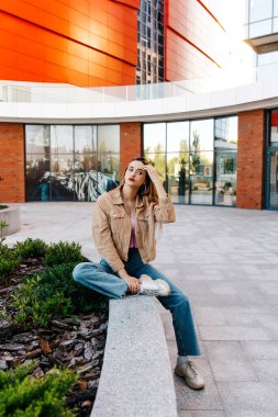 Şehirdeki kaldırımda oturan güzel genç kadın.