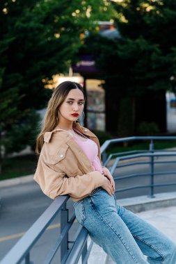 Güzel genç bayan korkuluklara yaslandı ve uzaklığa baktı.