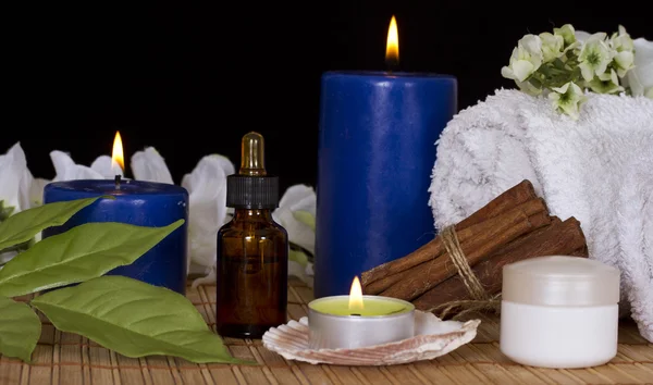 Garrafa com essência de spa, velas de spa, flores e creme — Fotografia de Stock