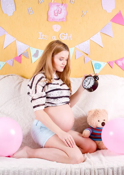 Concepto de embarazo. mujer embarazada feliz con un despertador en h —  Fotos de Stock