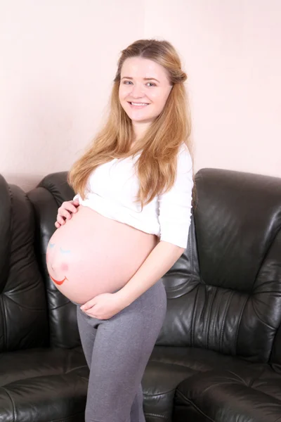 Femme enceinte avec un visage peint sur un lit d'estomac — Photo