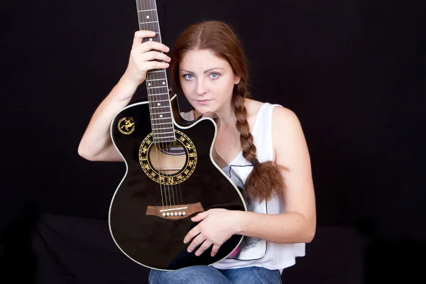 Bir gitar üzerinde siyah bir arka plan ile güzel kadın — Stok fotoğraf
