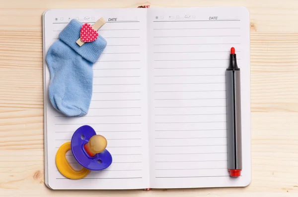 Notepad and baby shoes - top view — Stock Photo, Image