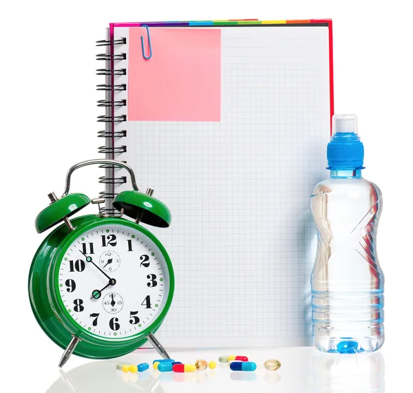 Alarm clock with notebook and pills — Stock Photo, Image