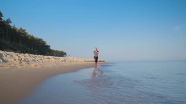 Kadın deniz sahilinde koşuyor.