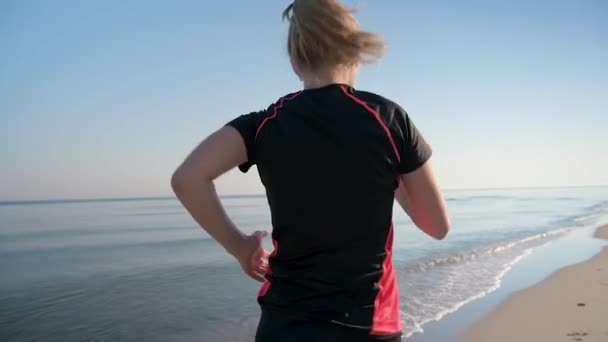 Женщина бегает по морскому пляжу — стоковое видео