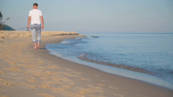 Человек с удочкой на пляже — стоковое видео