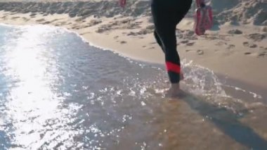 Sahilde çıplak ayaklı bir kadın yürüyor.