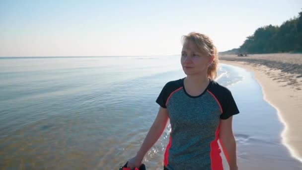 Босонога жінка, що йде на пляжі — стокове відео