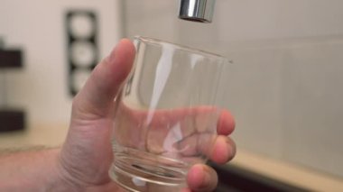 Adam bir bardak su dolduruyor.