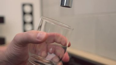 Adam bir bardak su dolduruyor.