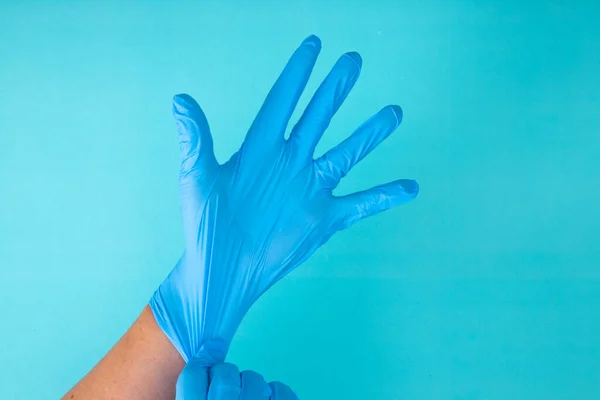 Doctor\'s hands wear rubber gloves on a blue background