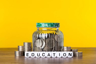 Cam para kavanozunda sarı arka planda bir sürü bozuk para var. Eğitim için Tasarruf.