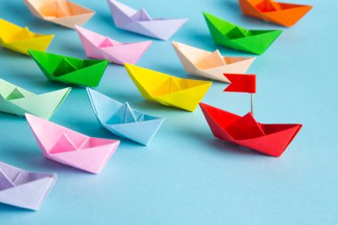 Liderlik kavramı. Kırmızı lider kağıt gemi mavi arka planda diğerleri arasında lider.
