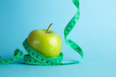 Diyet konsepti. Mavi arkaplanda elma ve mezura ölçüsü