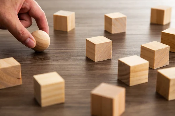 Yakın el ve ahşap küre, aşağı yerleştirmek için doğru konumu bulmaya çalışın..