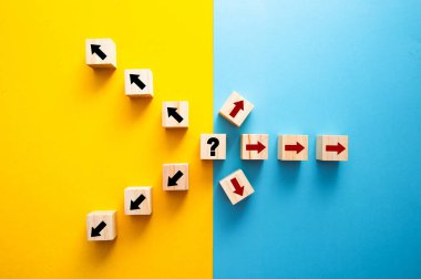 Wooden cubes with arrows representing choice, direction, and uncertainty on a split background