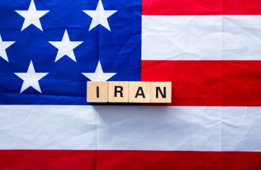 Tahta bloklar İran 'ı uluslararası ilişkileri ve gerilimi temsil eden buruşuk Amerikan bayrağına yazıyorlar.