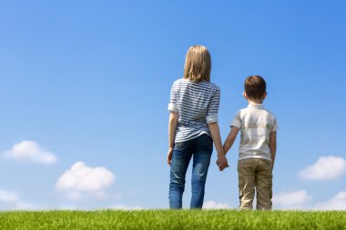 Arka plan gökyüzü, çimlerin üzerine elini tutarak kardeş